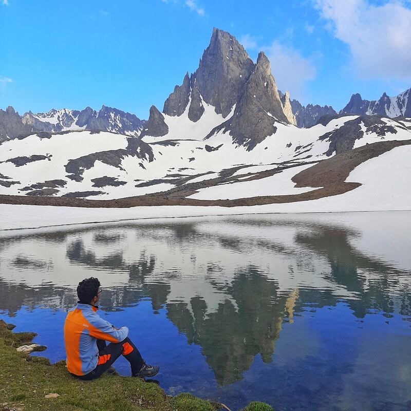 Zabih Afzali sits at the edge of a lake at the Mount Shah Fuladi base camp, June 2020. Courtesy Zabih Afzali