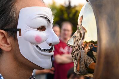 A man wearing a Guy Fawkes mask attends the unveiling of the bronze sculpture. AFP