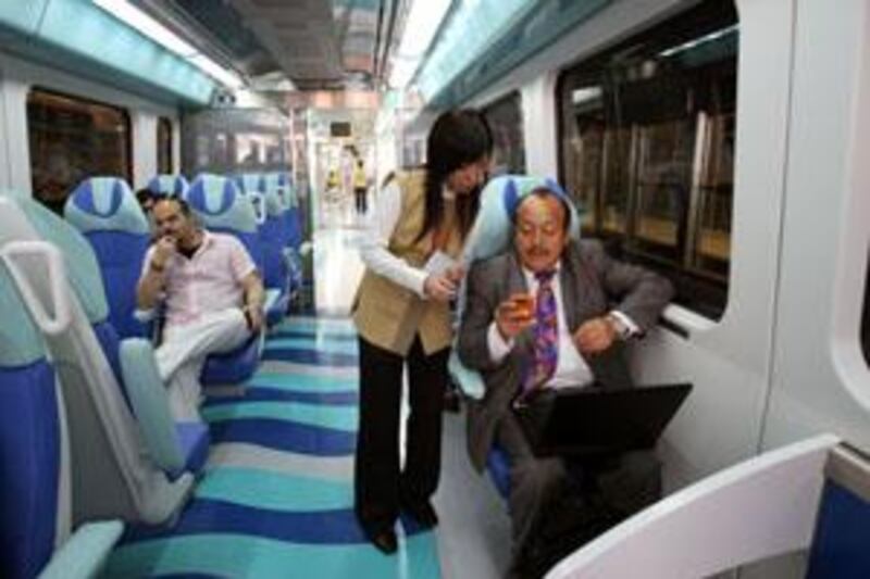 DUBAI, UNITED ARAB EMIRATES - SEPTEMBER 10:  Patricio Porras, an expat from Ecuador speaks with Shuang Li, from China, a train attendant, on board the first train of the day on the Dubai Metro network which pulled out of the Nakheel  Harbour & Tower station at 6am in Dubai on September 10, 2009. Ten metro stations on the Red Line officially opened to the public this morning.  (Randi Sokoloff / The National)  For news story by Jonathan Gornall/Stock- Dubai Metro