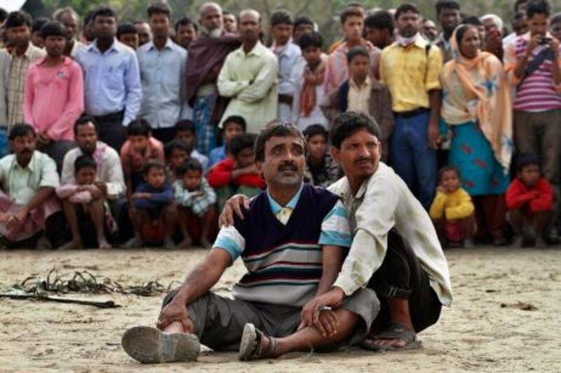 Abdul Mazid, 42, center, whose sister is missing anxiously watches rescuers pull out the wreckage of a ferry that capsized in the Brahmaputra River at Buraburi village, about 350 kilometers (215 miles) west of the state capital Gauhati, India, Tuesday, May 1, 2012. Army divers and rescue workers pulled more than 100 bodies out of a river after a packed ferry capsized in heavy winds and rain in remote northeast India, an official said Tuesday. At least 100 people were still missing Tuesday after the ferry carrying about 350 people broke into two pieces late Monday, said Pritam Saikia, the district magistrate of Goalpara district. (AP Photo/Anupam Nath) *** Local Caption ***  APTOPIX India Boat Accident.JPEG-0bb0e.jpg