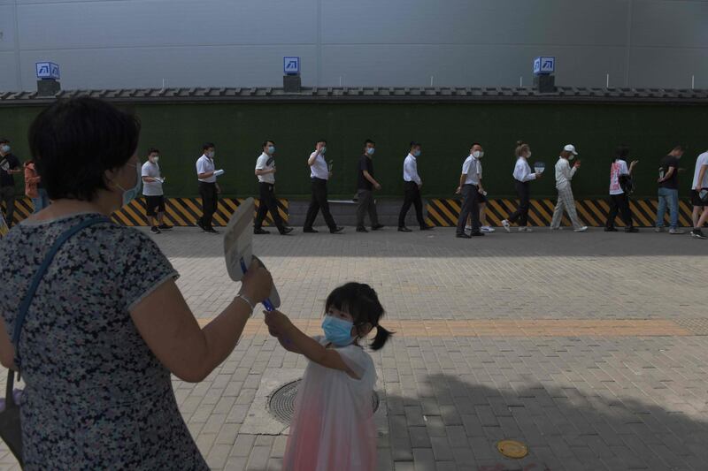 People wait in line to undergo coronavirus tests in Beijing. AFP