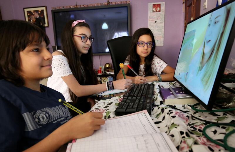 Children continue their school curriculum online via a computer screen at their home in Kuwait City. 
 AFP