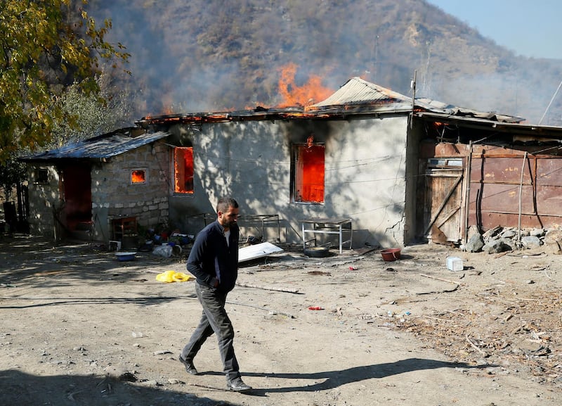 A local resident walks past a house set on fire by departing Ethnic Armenians, in an area which had held under their military control but is soon to be turned over to Azerbaijan.  Reuters