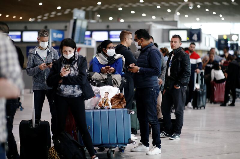 Masked travellers stand in line with luggage before getting to the Air France ticket counter at Paris Charles de Gaulle airport, following the coronavirus disease (COVID-19) outbreak, in Roissy-en-France, France March 16, 2020. REUTERS/Benoit Tessier