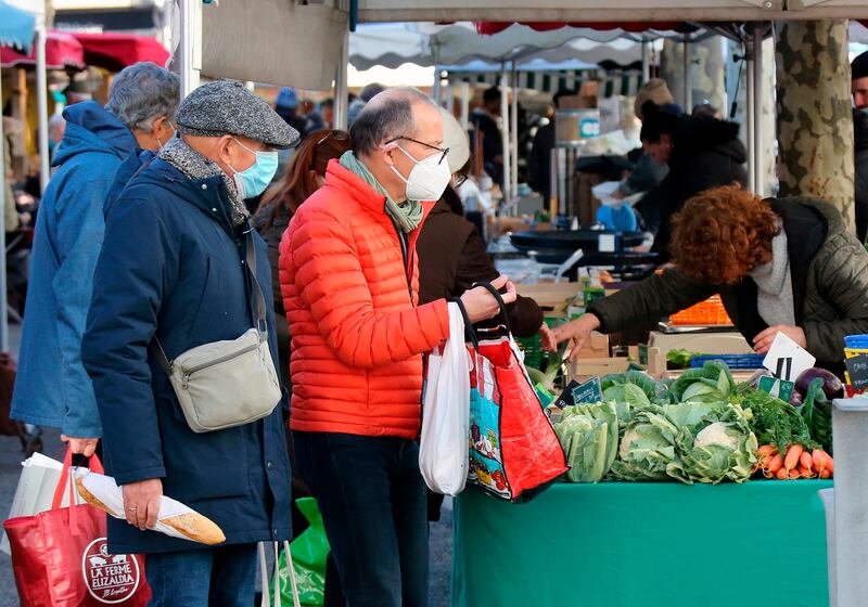 People wearing face mask at a farmers market in Saint Jean de Luz, southwestern France, Friday, January 14, 2022.  In France, the outdoor mask mandate was partially reinstated in December in many cities, including Paris.  The age for children to start wearing masks in public places was lowered to 6 from 11.  AP