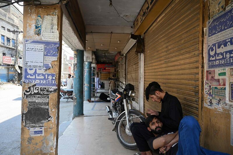 Shopkeepers sit along a closed market after a nine-day shutdown was imposed in a bid to prevent a surge in Covid-19 coronavirus cases during the Muslim holiday of Eid al-Fitr in Rawalpindi on May 8, 2021.  / AFP / Farooq NAEEM
