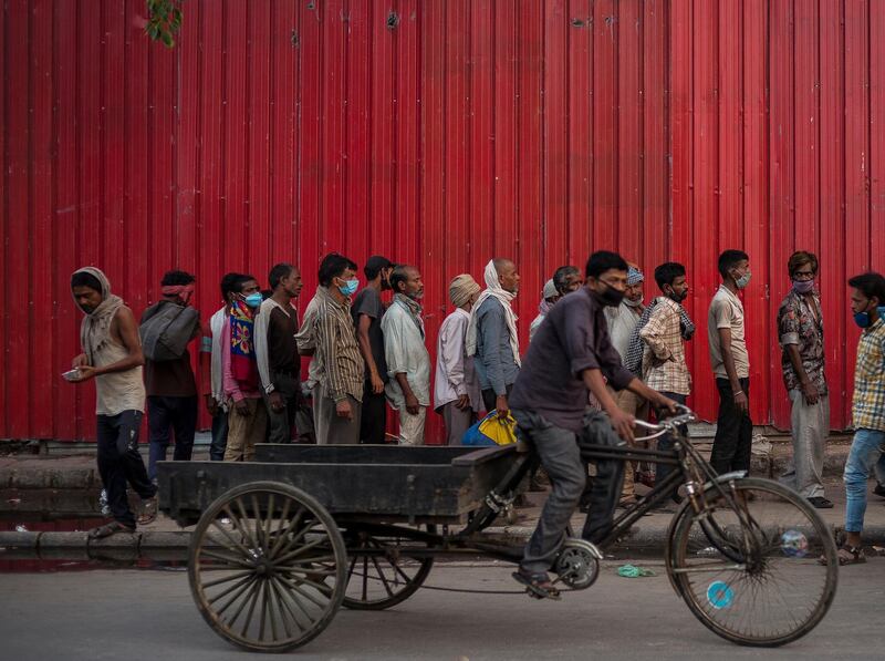Rickshaw-pullers and other migrant labourers queue up to receive food distributed by a charity as the lockdown continues in New Delhi. Getty Images