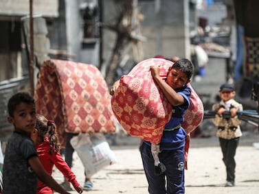 Palestinian children carrying their belongings arrive in Khan Yunis in the southern Gaza Strip to seek shelter on May 18, 2024, amid the ongoing conflict between Israel and the Palestinian Hamas movement.  (Photo by AFP)