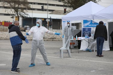 Israeli employees of the Central Elections Committee and the Magen David Adom (MDA), Israel's national emergency medical services, wearing protective suits guide voters to a special sterile voting station for people in quarantine on coronavirus suspicion, in Jerusalem, Israel, 2 March, 2020. EPA