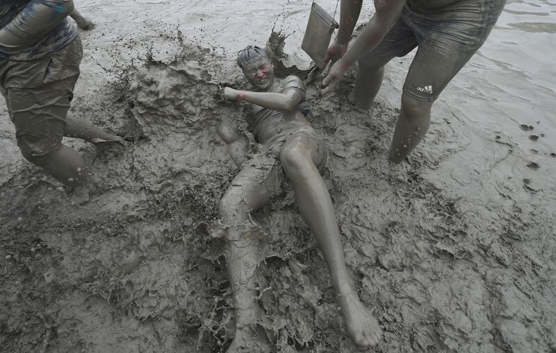 A reveller writhes around in the greyish sludge at the festival. Jung Yeon-Je