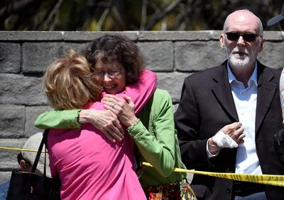 Synagogue members hug as a man with a hand injury looks on outside of the Chabad of Poway Synagogue Saturday, April 27, 2019, in Poway, Calif. Several people were injured in a shooting at the synagogue. (AP Photo/Denis Poroy)