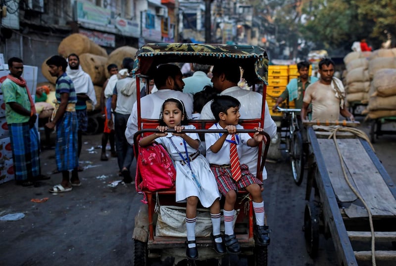 School children ride in a cycle rickshaw through a market in the old quarters of Delhi, India. Reuters