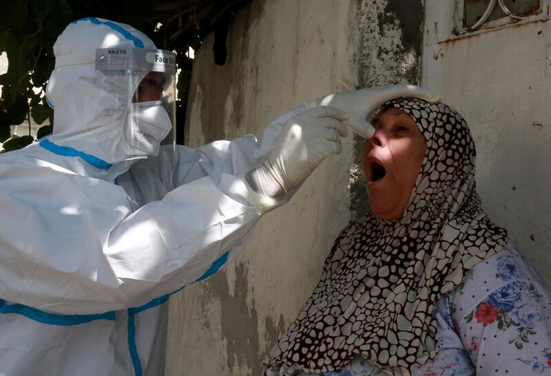 A woman reacts as a swab sample is taken from her nose for COVID-19 coronavirus disease in a suburb of the Jordanian capital Amman, after a hike in the number of infections, on September 4, 2020.   / AFP / Khalil MAZRAAWI
