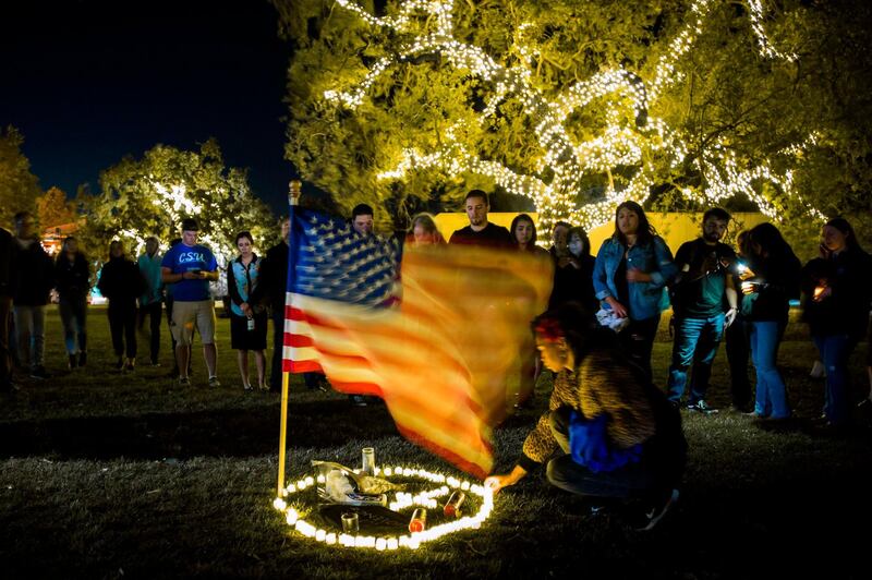 A woman places a candle in the grass next to a US flag during a vigil to pay tribute to the victims of the shooting. AFP