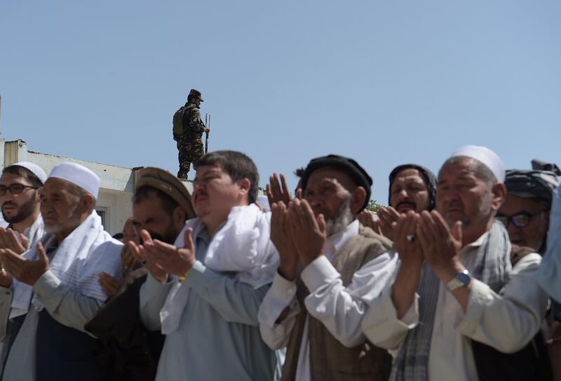 A security guard keeps watch as Afghan mourners and relatives pray in front of the coffin of one of the 28 victims of a suicide attack, on a Shiite mosque a day earlier, in Kabul on August 26, 2017.
Hundreds of Shiite mourners began burying the victims of a suicide bomb and gun attack on a Kabul mosque on August 26 as the death toll from the atrocity rose to 28.Distraught relatives and friends carried coffins into the cemetery one by one, a day after the latest deadly attack claimed by the Islamic State group on Afghanistan's reeling minority Shiite community. / AFP PHOTO / SHAH MARAI