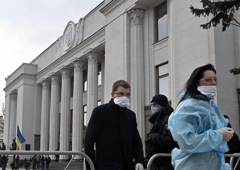 Ukrainian lawmakers wearing face mask and protective suit, amid concerns over the spread of the COVID-19 coronavirus, leave the parliament after an extraordinary sitting on March 30, 2020. Ukraine announced on Monday a sharp revision of this year's economic forecast from 3.7 percent growth to a 3.9 percent contraction due to the novel coronavirus.  / AFP / Sergei SUPINSKY
