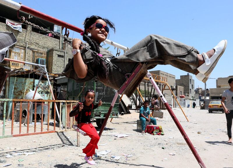 Iraqi children play on a swing during Eid al-Fitr celebrations at a popular amusement park in Sadr city in Baghdad, Iraq. Ali Abbas / EPA