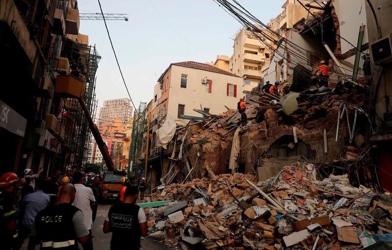 Onlookers gather as rescue workers dig through the rubble of a badly damaged building in  Lebanon's capital Beirut in search of possible survivors from a mega-blast at the adjacent port one month ago. AFP