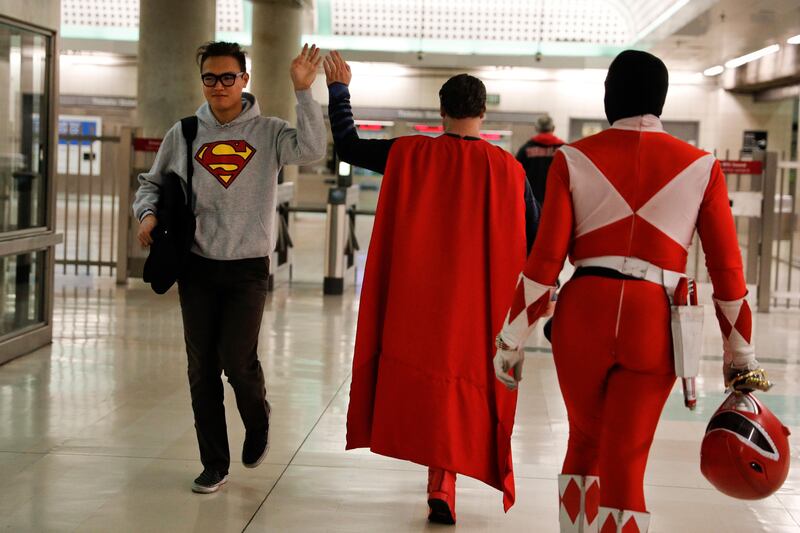 Superman impersonator Justin Harrison, centre, high-fives a commuter wearing a sweatshirt with a Superman symbol printed on it as he and his roommate, Reginald Jackson, in a Red Power Ranger costume, head back home after working on Hollywood Boulevard, in Los Angeles. "When I put on any costume of any character, I automatically feel like I am that character," said Harrison. Jae C Hong / AP Photo