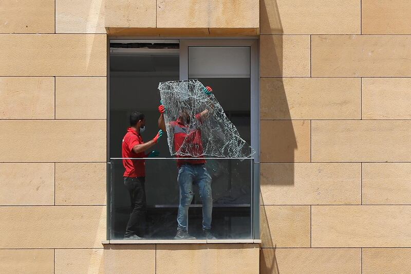 Workers throw a broken window from a damaged apartment a day after an explosion hit the seaport of Beirut. AP Photo