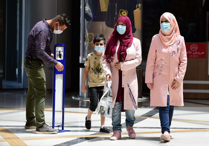 Iraqis use sanitisers before entering a reopened shopping mall in central Baghdad. EPA