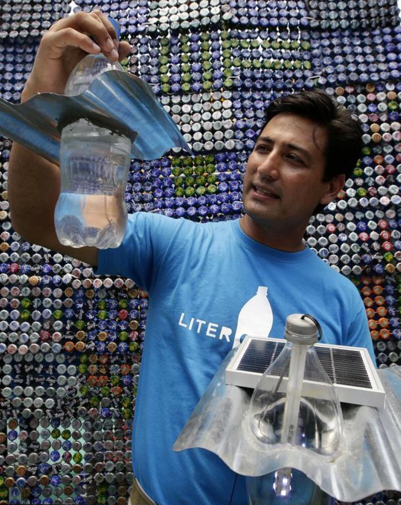 Illac Diaz holds a recycled plastic water container, left, and another container housing an inexpensive solar powered bulb. Both can be used to light homes for as long as five hours.  Bullit Marquez / AP Photo 