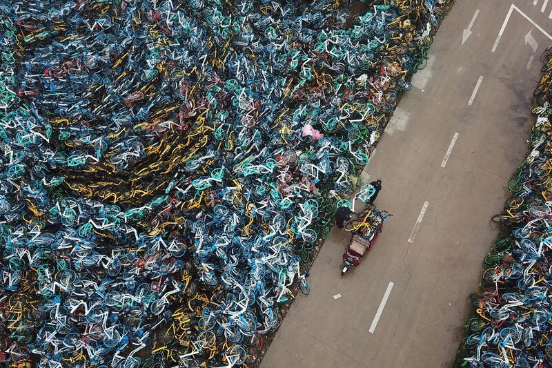 Urban management officers move among piled-up bicycles from bike-sharing services in Hefei, Anhui province, China. Reuters