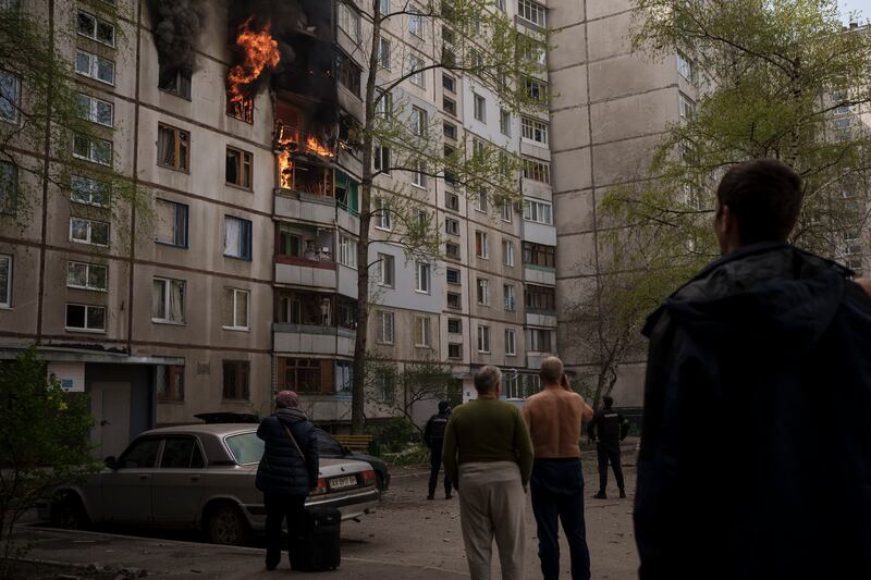 People watch as a residential building burns after Russian bombardment in Kharkiv, Ukraine. AP