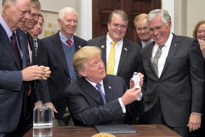 US President Donald Trump holds up an astronaut toy alongside former US Senator and Apollo 17 Astronaut Jack Schmitt (R), after a signing ceremony for Space Policy Directive 1, with the aim of returning Americans to the Moon, in the Roosevelt Room at the White House in Washington, DC, December 11, 2017. / AFP PHOTO / SAUL LOEB