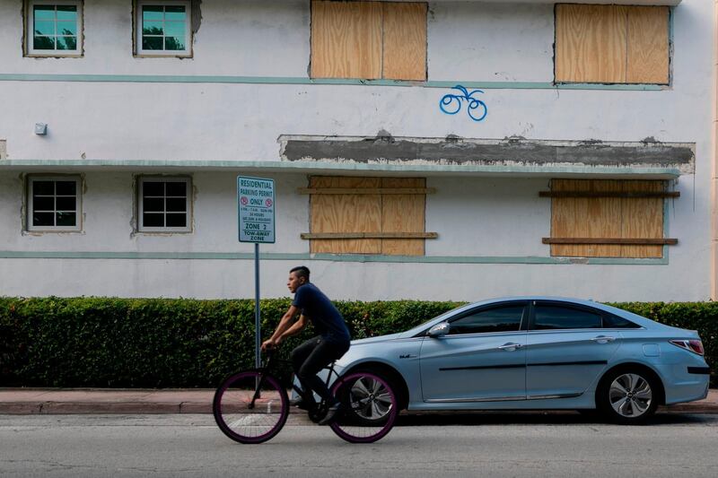 A man rides a bike by a building with boarded up windows during a hurricane alert in South Miami Beach, Florida. AFP