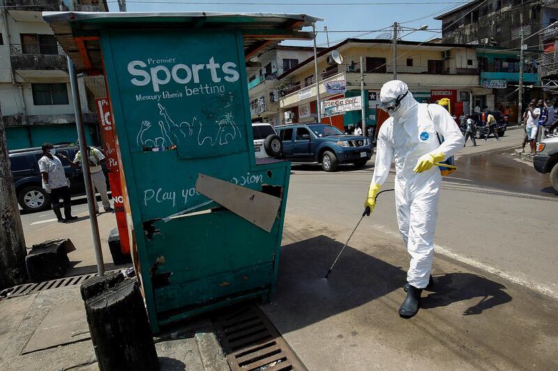 A Liberian health worker disinfects a street corner where a suspected Ebola patient was picked up and taken into an ambulance to be transported to an Ebola treatment unit in Monrovia, Liberia, on October 23, 2014. EPA