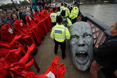 Environmental protestors gather around the head of a statue confiscated by police on Lambeth bridge in central London Monday, October 7, 2019. AP Photo/Matt Dunham