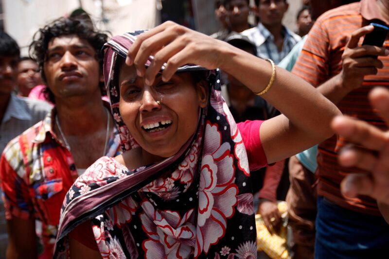 epa03674796 A woman cries on the site of the damaged building as she watches the rescue operation after the eight-storey Rana Plaza building collapsed at Savar in Dhaka, Bangladesh, 24 April 2013. At least 20 people died including garment workers and many more were critically injured, reports said.  EPA/ABIR ABDULLAH *** Local Caption ***  03674796.jpg