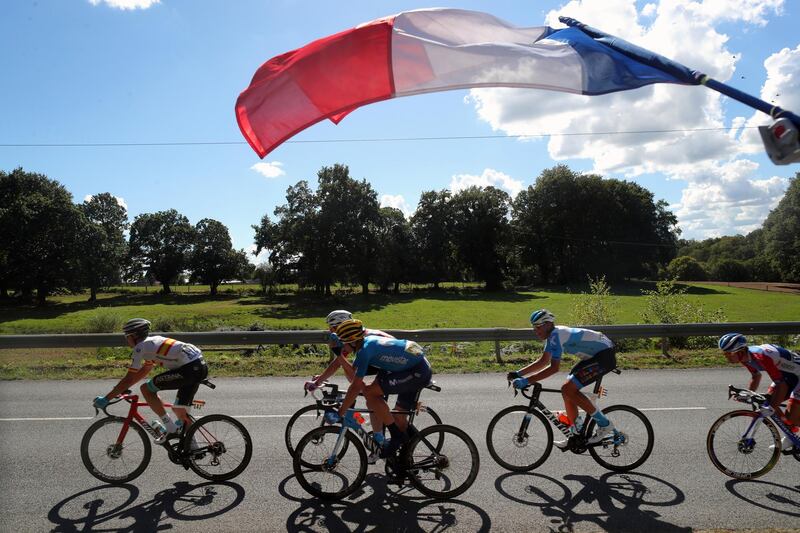 A French flag flies over riders during Stage 12. AP