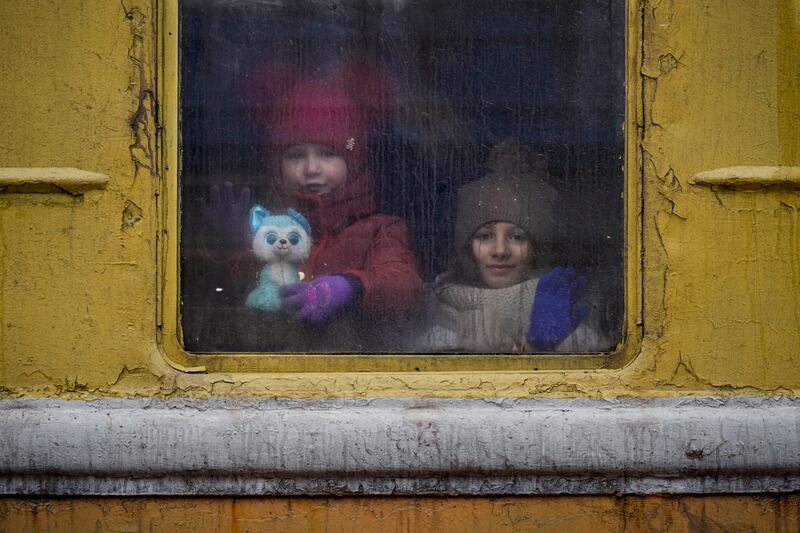 A woman and child look out the window of a train at a station in Kyiv. AP