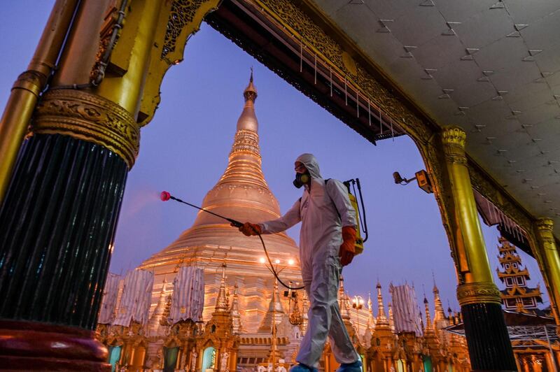 A volunteer sprays disinfectant in Shwedagon Pagoda compound as a preventive measure against the COVID-19 coronavirus, in Yangon.  AFP