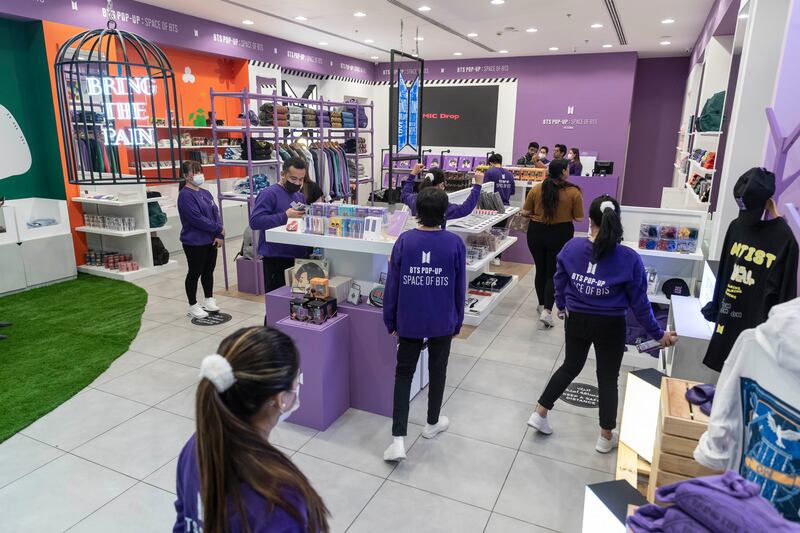 Shop assistants, dressed in purple, the official colour of BTS, help customers. 