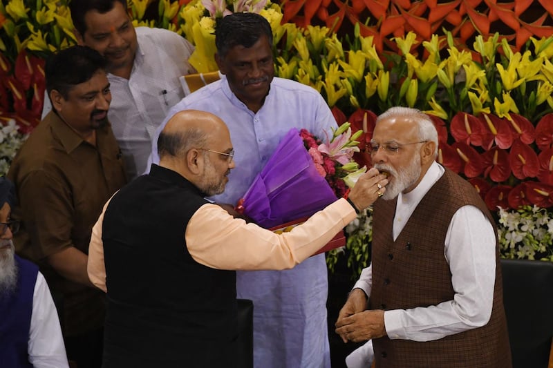 Bhartiya Janta Party (BJP) President Amit Shah feeds sweets to Indian Prime Minister Narendra Modi (L) gesture during a National Democratic Alliance (NDA) meeting at the central hall of the parliament, in New Delhi on May 25, 2019.  Modi has been formally elected as leader of the Bhartiya Janta Party (BJP) led National Democratic Alliance (NDA) during the meeting. / AFP / PRAKASH SINGH
