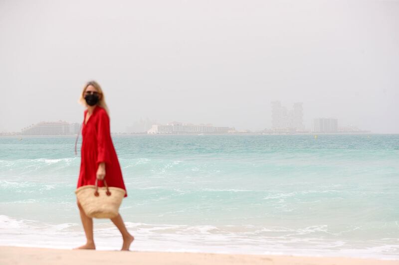 Dubai, United Arab Emirates - Reporter: N/A. News. Weather. A lady walks on the beach on a hazy sandy day in Dubai. Sunday, March 14th, 2021. Dubai. Chris Whiteoak / The National