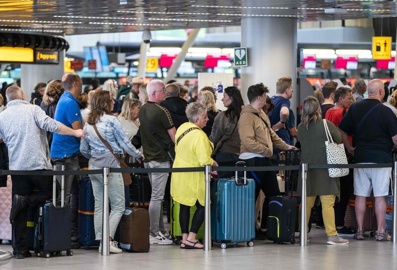 Travellers queue at Amsterdam Airport Schiphol, where staff shortages have led to passengers missing flights. AFP