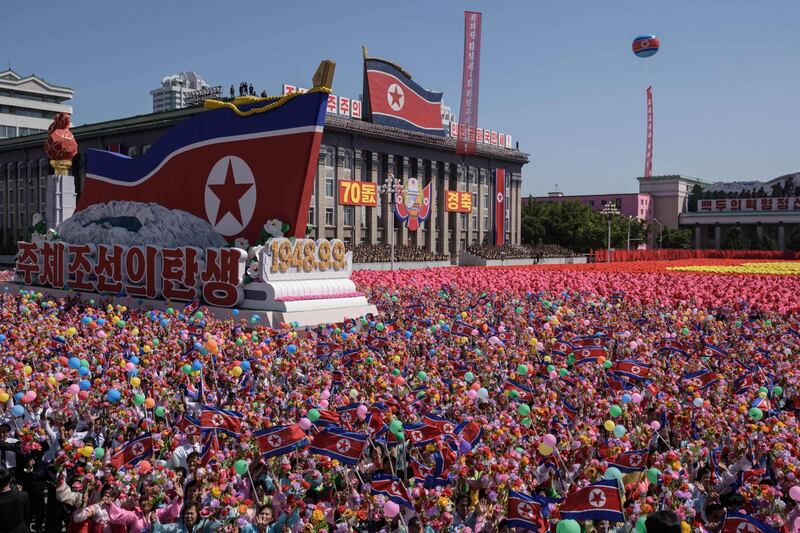 Participants wave flowers as they march past a balcony from where North Korea's leader Kim Jong Un was watching, during a mass rally on Kim Il Sung square in Pyongyang.  AFP