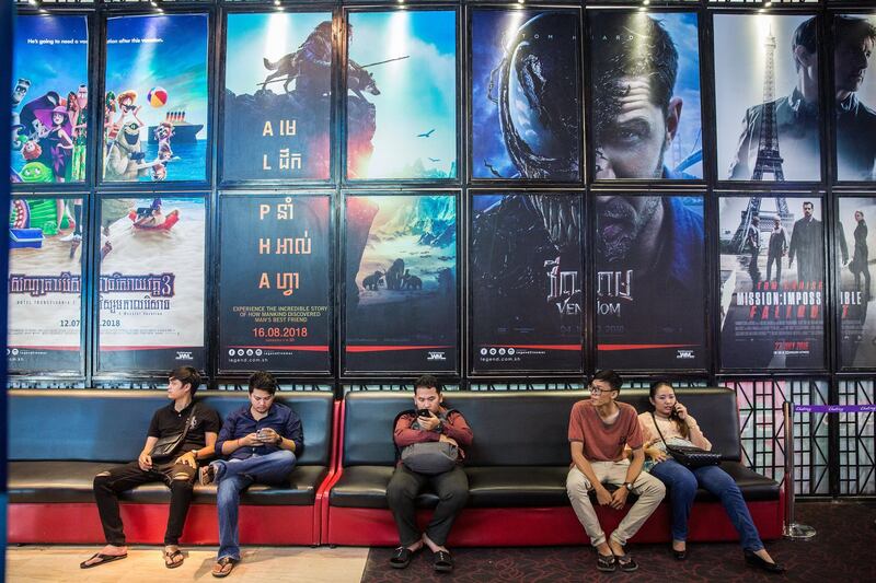Customers sit in front of movie posters at a Legend Cinema outlet at the T.K. Avenue shopping area in Phnom Penh, Cambodia, on Thursday, July 26, 2018. Cambodian Prime Minister Hun Sen extended his more-than-three-decade run in power, easily winning a boycotted election on July 29 after he disbanded the main opposition party last year. Photographer: Taylor Weidman/Bloomberg