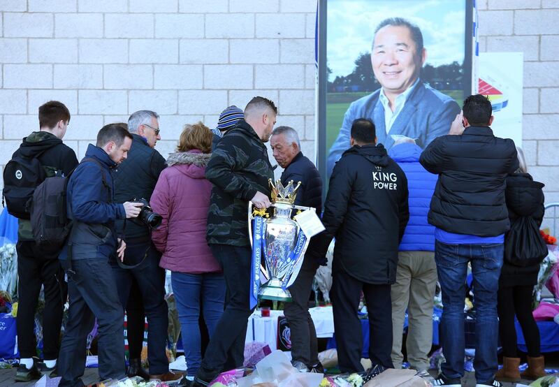 People with a replica of the Premier League trophy look over flowers, tributes and messages of condolence outside the King Power stadium in Leicester, Britain. EPA
