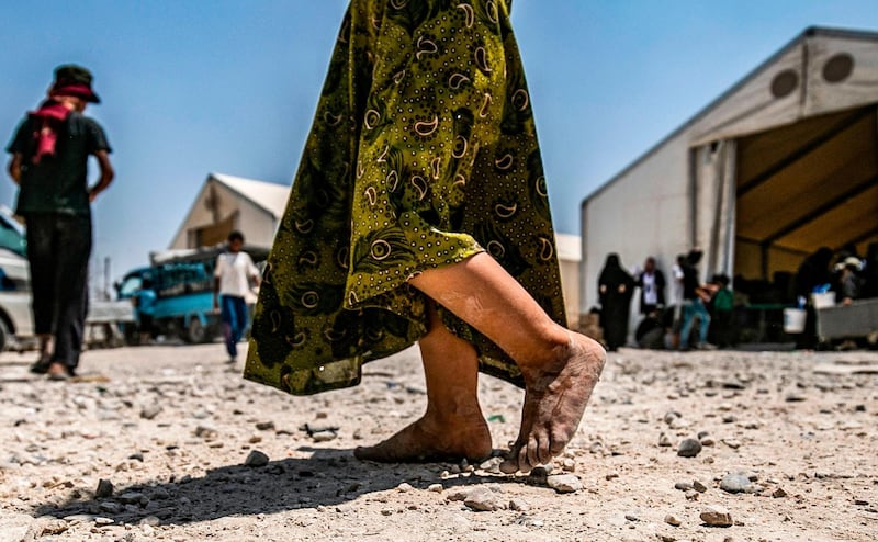 (FILES) In this file photograph taken on July 22, 2019, a young child walks barefoot at al-Hol camp for displaced people, in al-Hasakeh governorate, north-eastern Syria, as people collect UN-provided humanitarian aid packages. The government said June 22, 2020, that it had brought home 10 French children of jihadist fighters overnight from a refugee camp in Syria, the latest in a piecemeal repatriation process since the Islamic State group was ousted from its Syrian base in March 2019. / AFP / Delil souleiman
