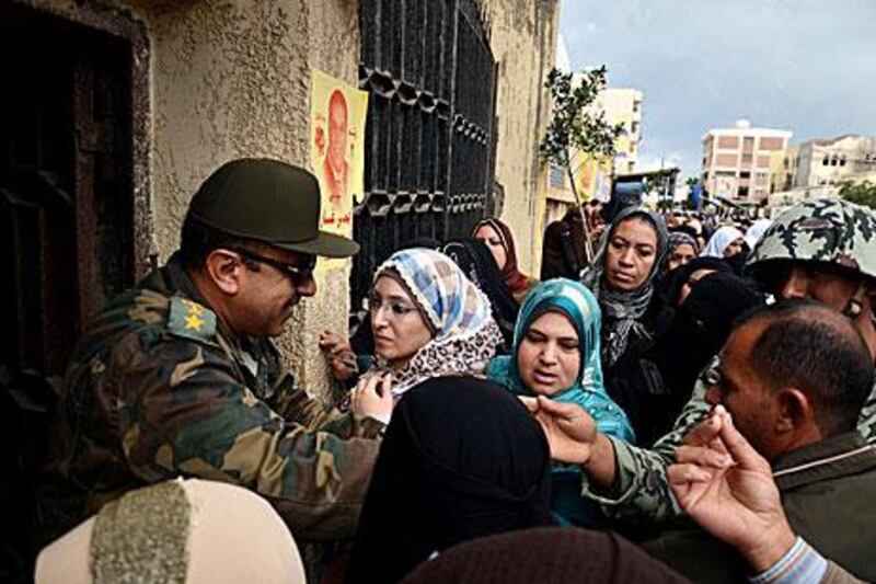 An Egyptian army officer stands at the entrance of a polling station as voters wait to enter on the first day of elections in Alexandria.