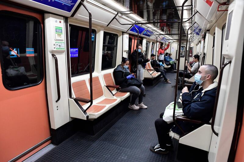 Commuters wearing face masks sit on a train at the Atocha Station in Madrid as some companies were set to resume operations at the end of a two-weeks halt of all non-essential activity.  AFP