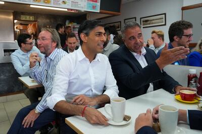 Rishi Sunak and Steve Tuckwell speak to locals in an Uxbridge cafe on Friday. Reuters 
