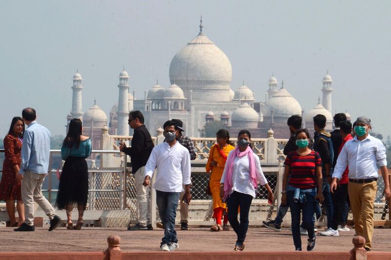 Tourists wear facemasks as a preventive measure against the spread of the COVID-19 coronavirus outbreak, near Taj Mahal in Agra on March 5, 2020. More than 95,000 people have been infected and over 3,200 have died worldwide from the new coronavirus, which by on March 5 had reached some 80 countries and territories. / AFP / Pawan Sharma
