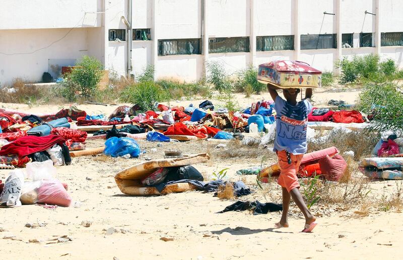 A Migrants collects his belongings from the destroyed detention centre in Tripoli's, Libya.  EPA