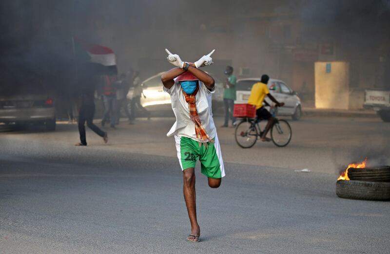A Sudanese protester clad in mask and latex gloves runs during a demonstration marking the first anniversary of a raid on an anti-government sit-in, in the Riyadh district in the east of the capital Khartoum.  AFP